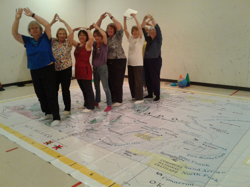 Members of the Colorado League of Women Voters perform the On the Move lesson on the Giant Map of Colorado.